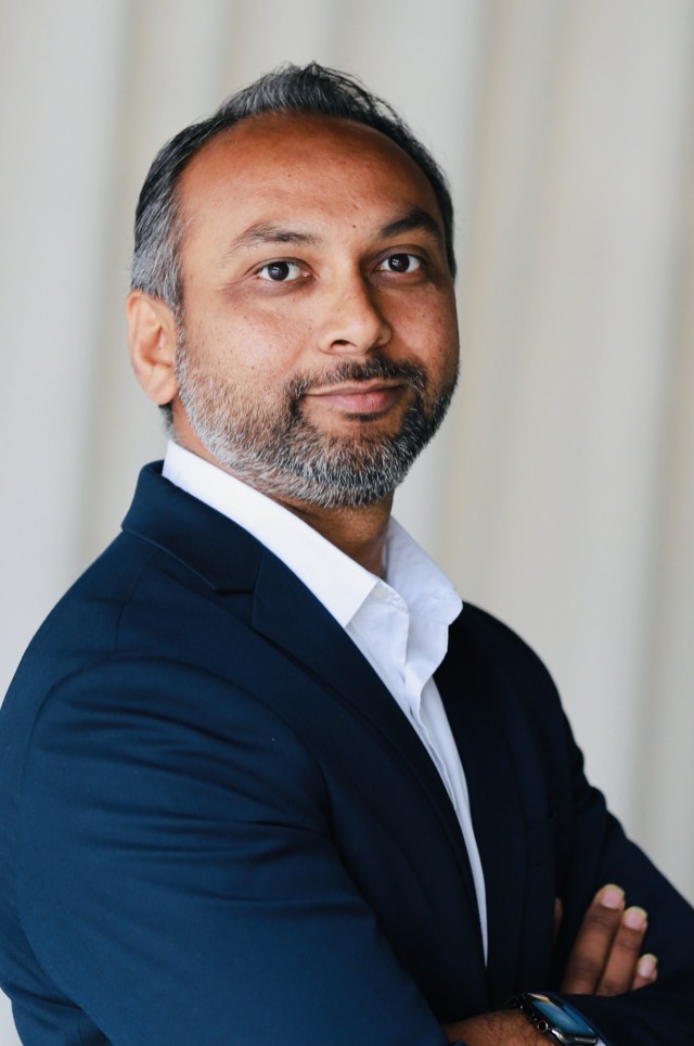 Anit Patel in a navy blazer with arms crossed, looking at the camera