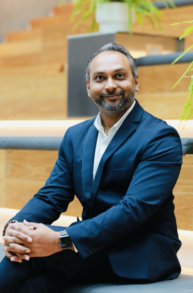 Anit Patel seated on timber steps, smiling